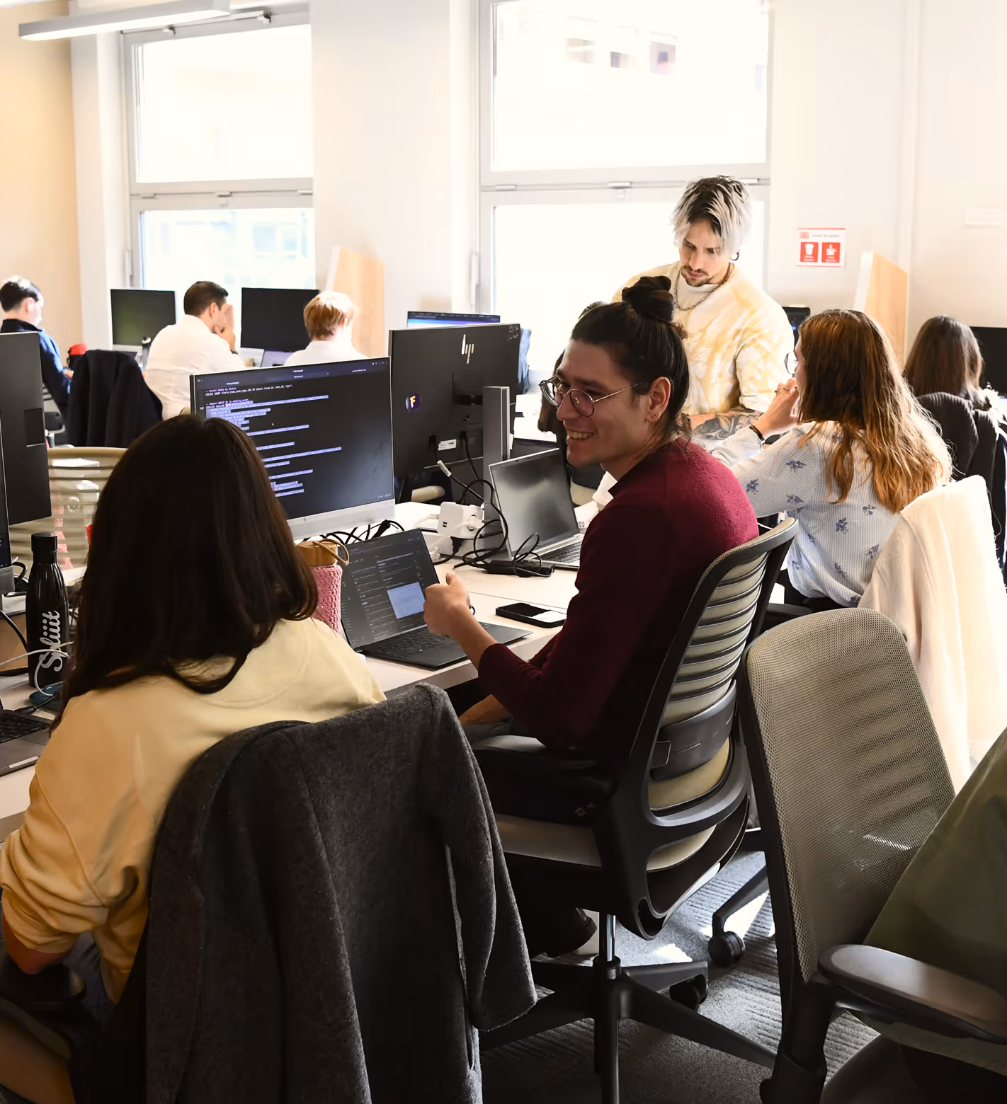 Équipe réunie autour d'ordinateurs dans un espace de travail lumineux